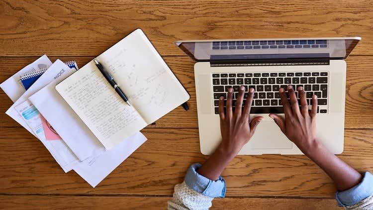 Student working on an academic essay with books, laptop, and research notes on a study desk