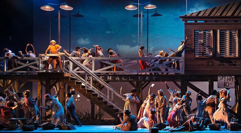 A dramatic stage scene representing Catfish Row from Porgy and Bess, with performers in a coastal community setting